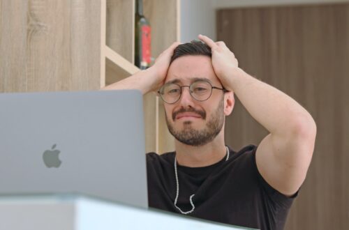 a man with glasses is looking at a laptop