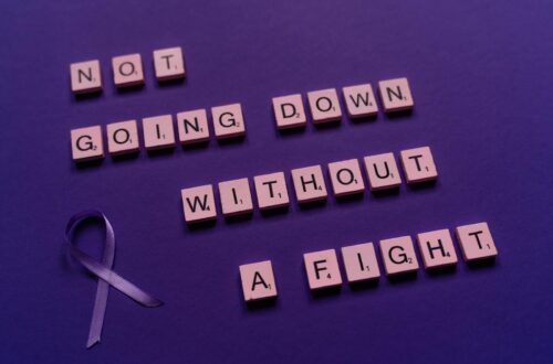 An inspirational quote made from Scrabble tiles alongside a purple awareness ribbon.